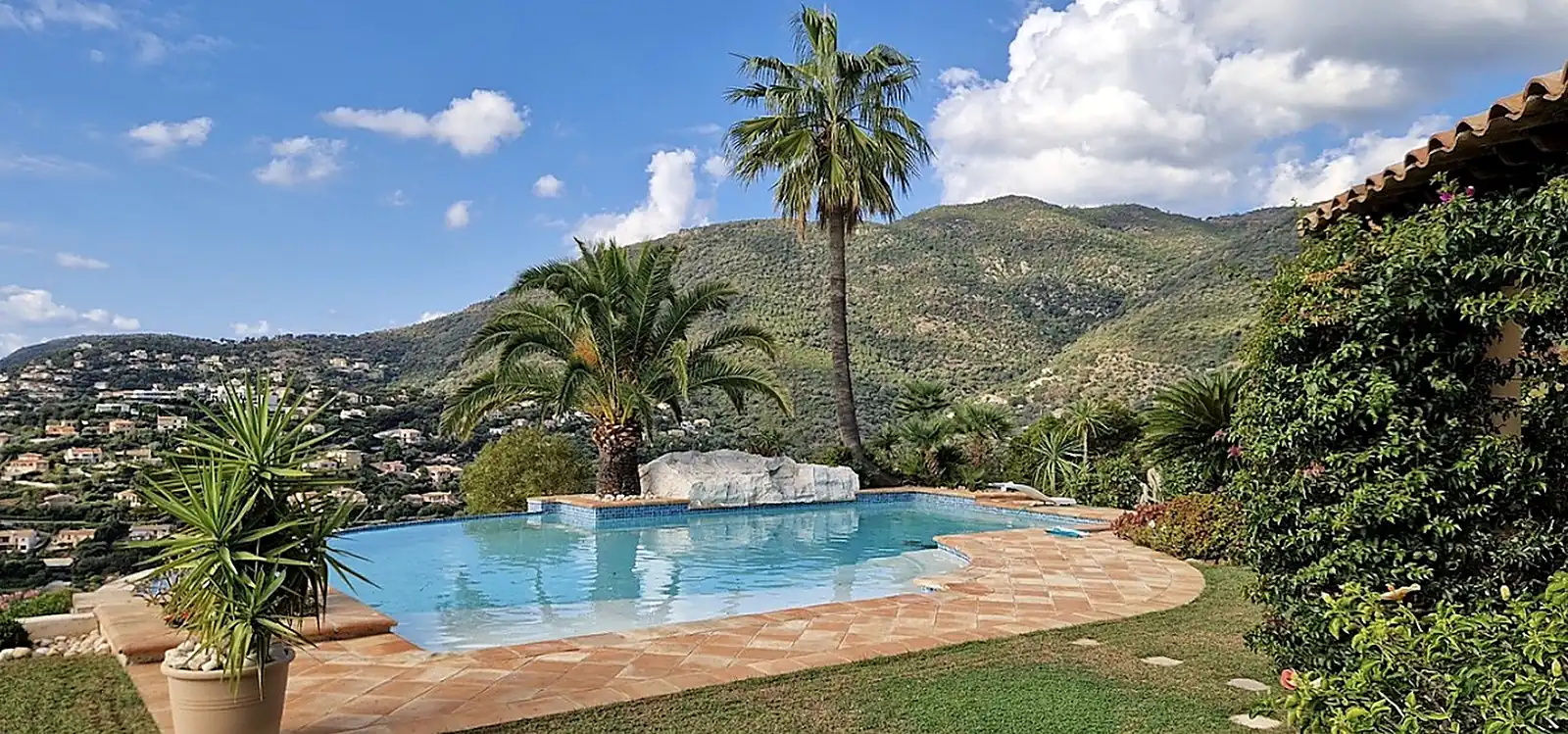 Piscine rénovée avec décor en faux rocher et margelles travertin, vue panoramique sur les collines à Nice, Côte d'Azur – HARTEC SUD