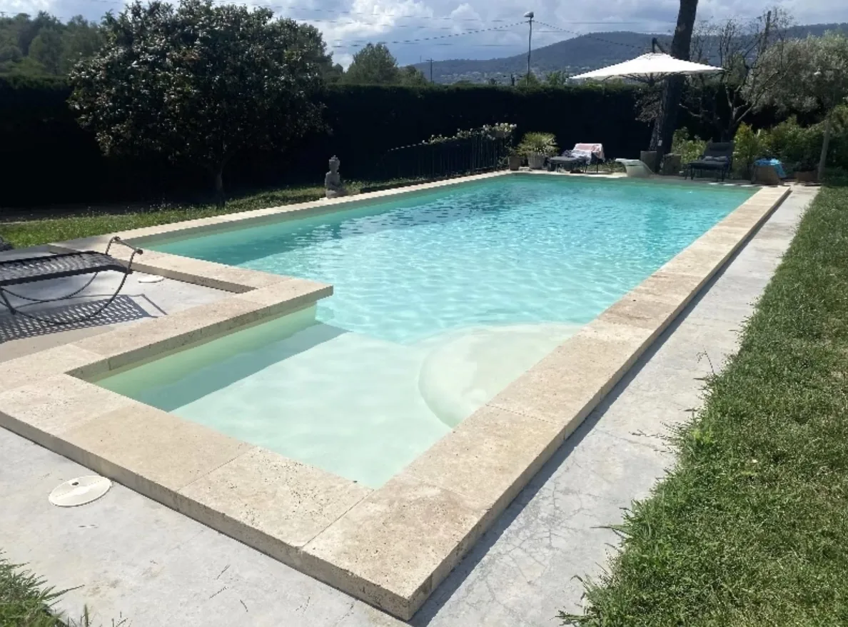 Piscine rectangulaire à l'eau turquoise avec margelles travertin après rénovation polyester sur la Côte d'Azur – HARTEC SUD
